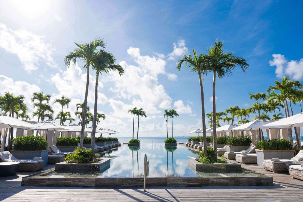 Infinity pool lined with palm trees facing the sea at a Playa del Carmen resort