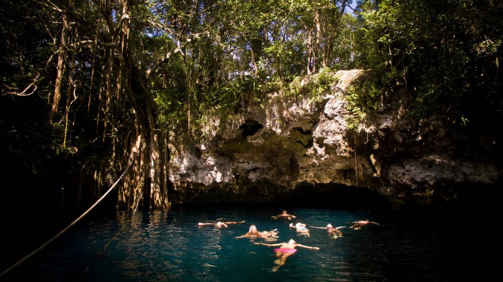 Aerial view of an open cenote surrounded by jungle