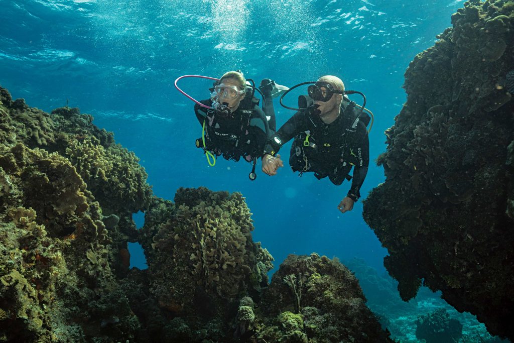 Two scuba divers drifting between coral formations in Cozumel