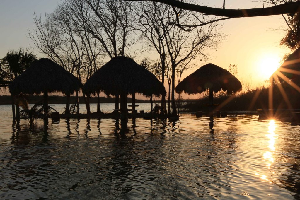 Palapas on the shore of a lagoon at sunset in Maya Ka'an